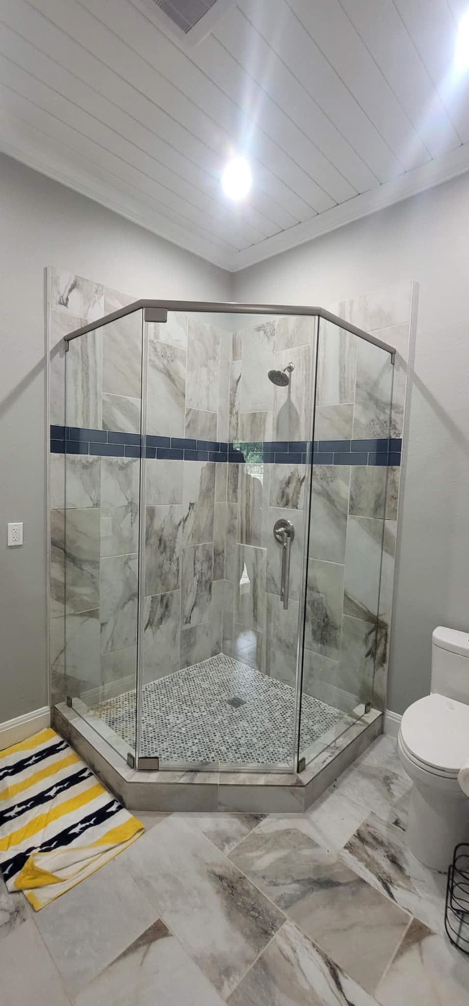 A newly constructed bathroom with a glass shower enclosure and a white toilet.