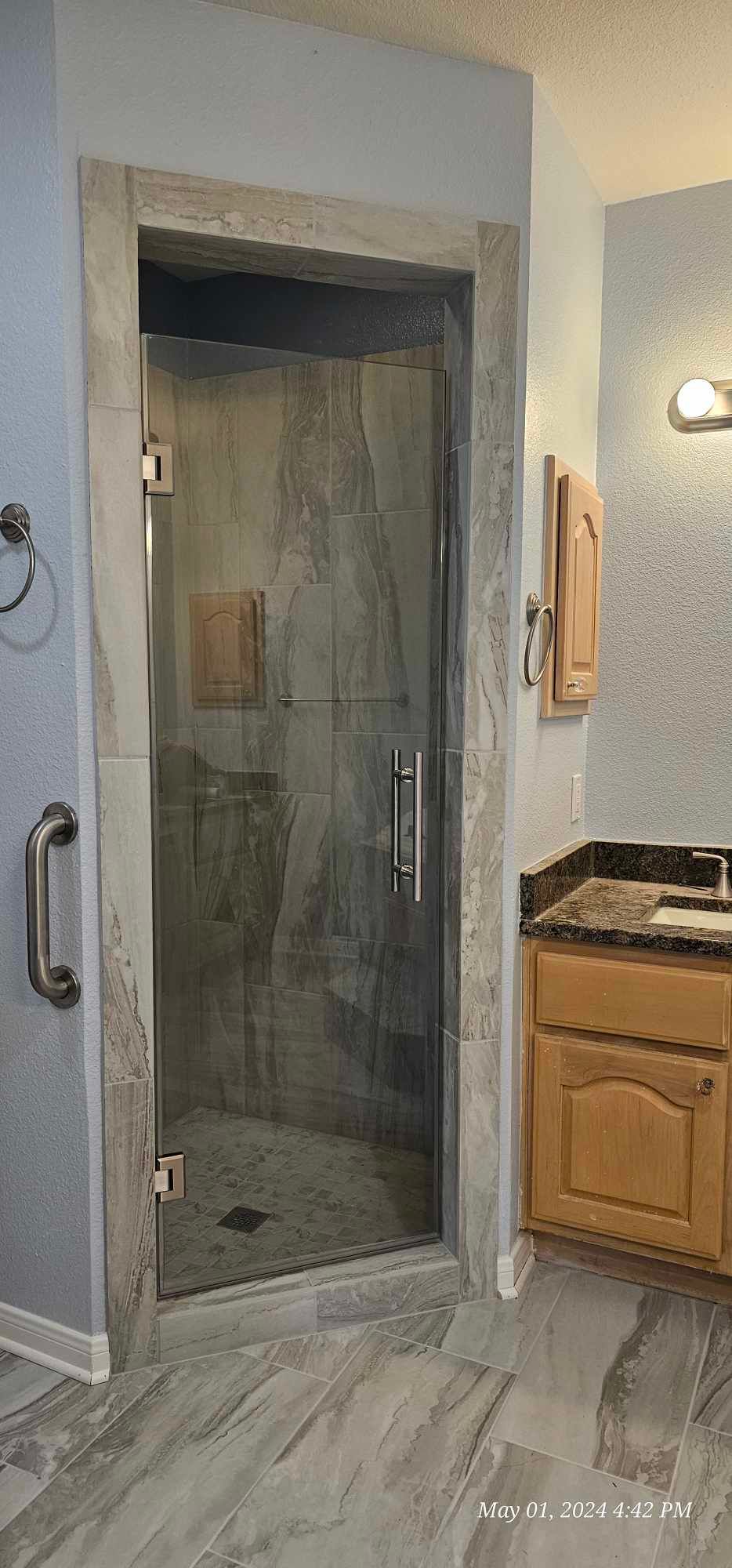 Bathroom with a glass shower door, beige cabinetry, and gray flooring.