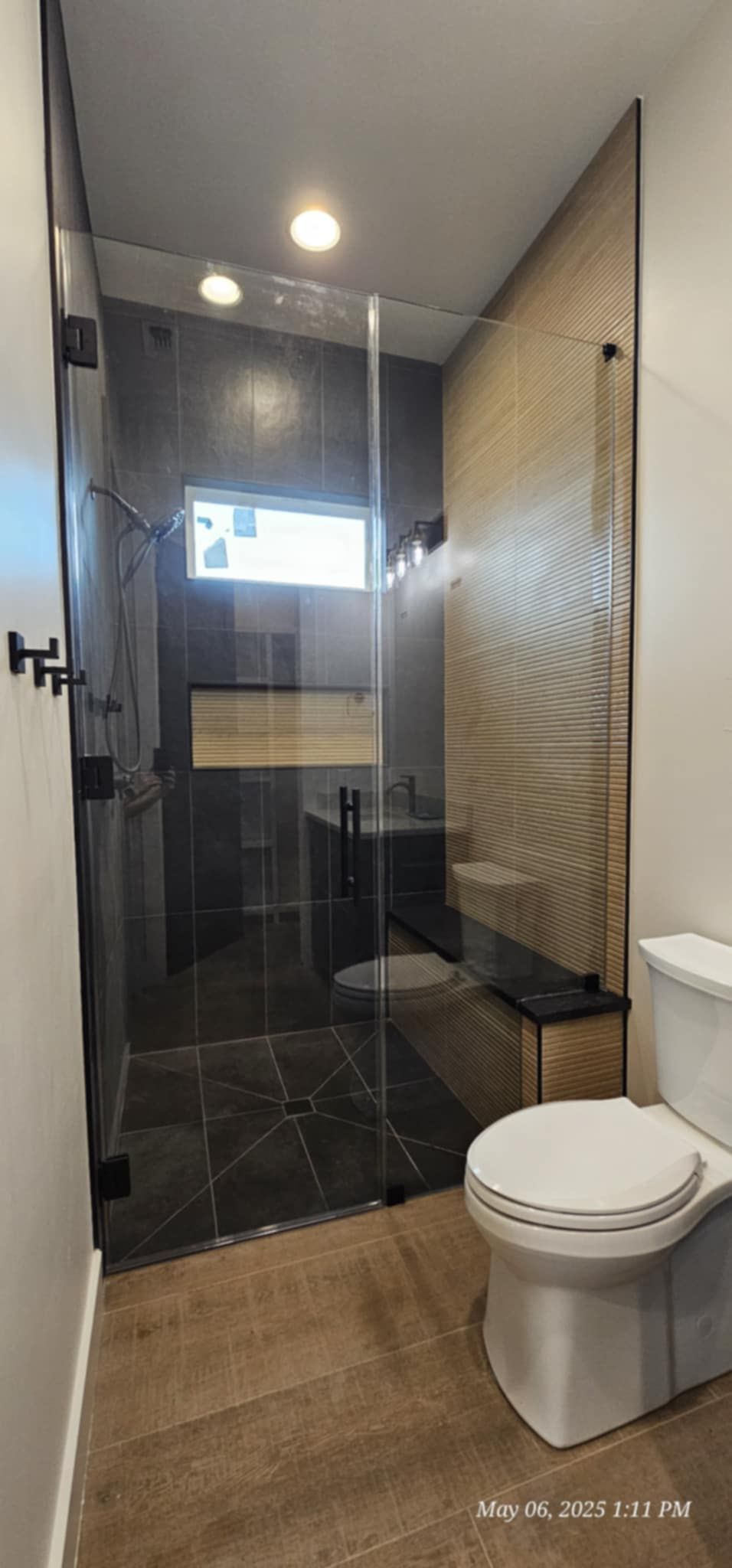 Modern bathroom with a glass-enclosed shower, a toilet, and a tiled wall.