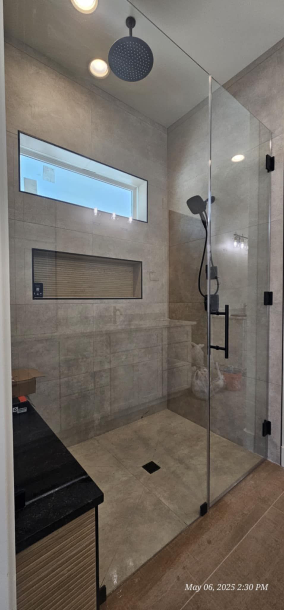Modern bathroom with a large glass shower enclosure and tiled walls.
