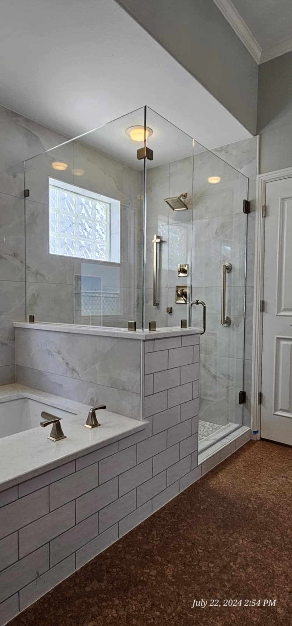 A luxurious bathroom with a glass shower, marble tile, and a built-in tub.