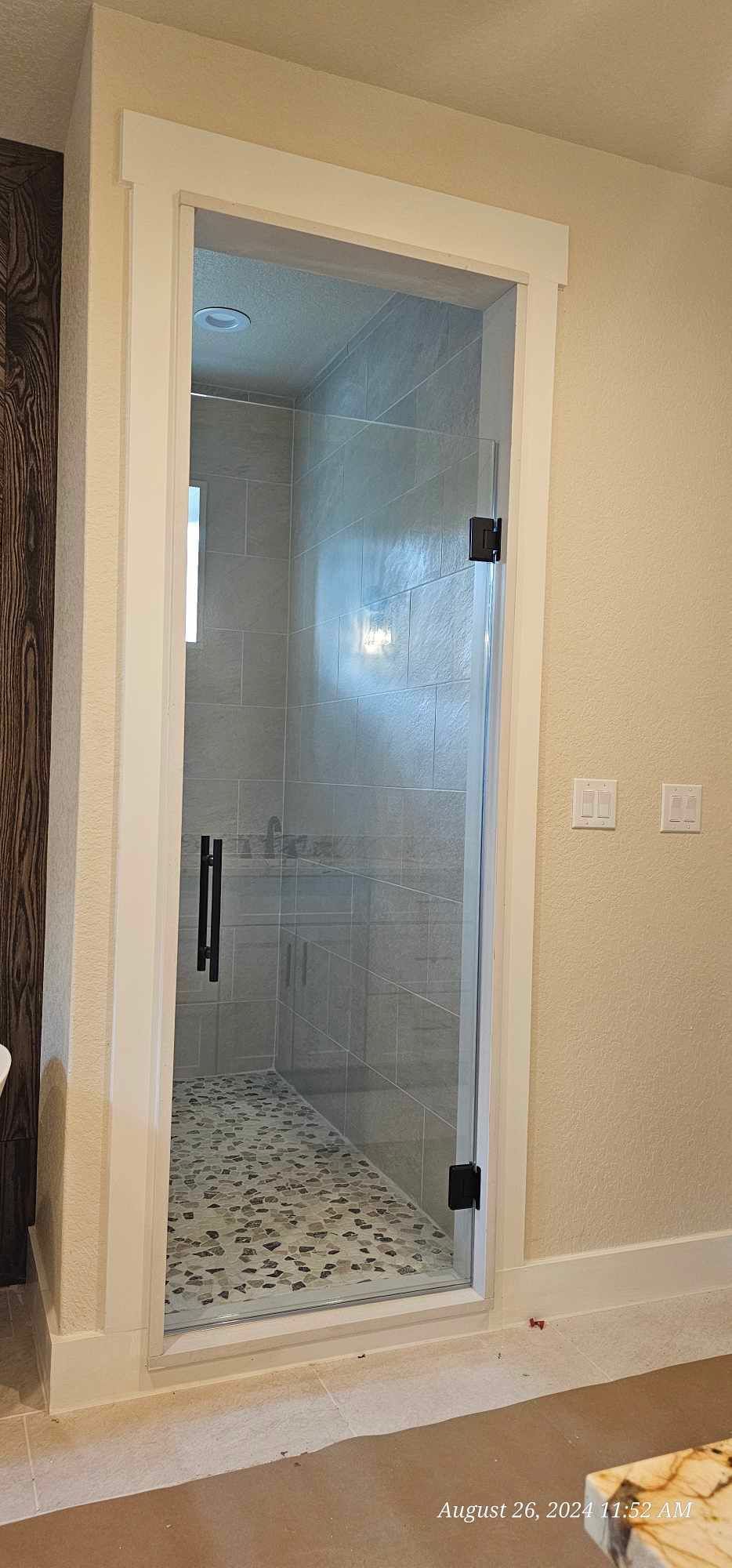 Framed glass shower door in a bathroom with pebble floor.