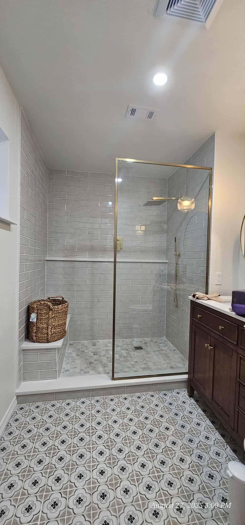Bathroom with mosaic tile shower, glass door, vanity, and patterned floor.