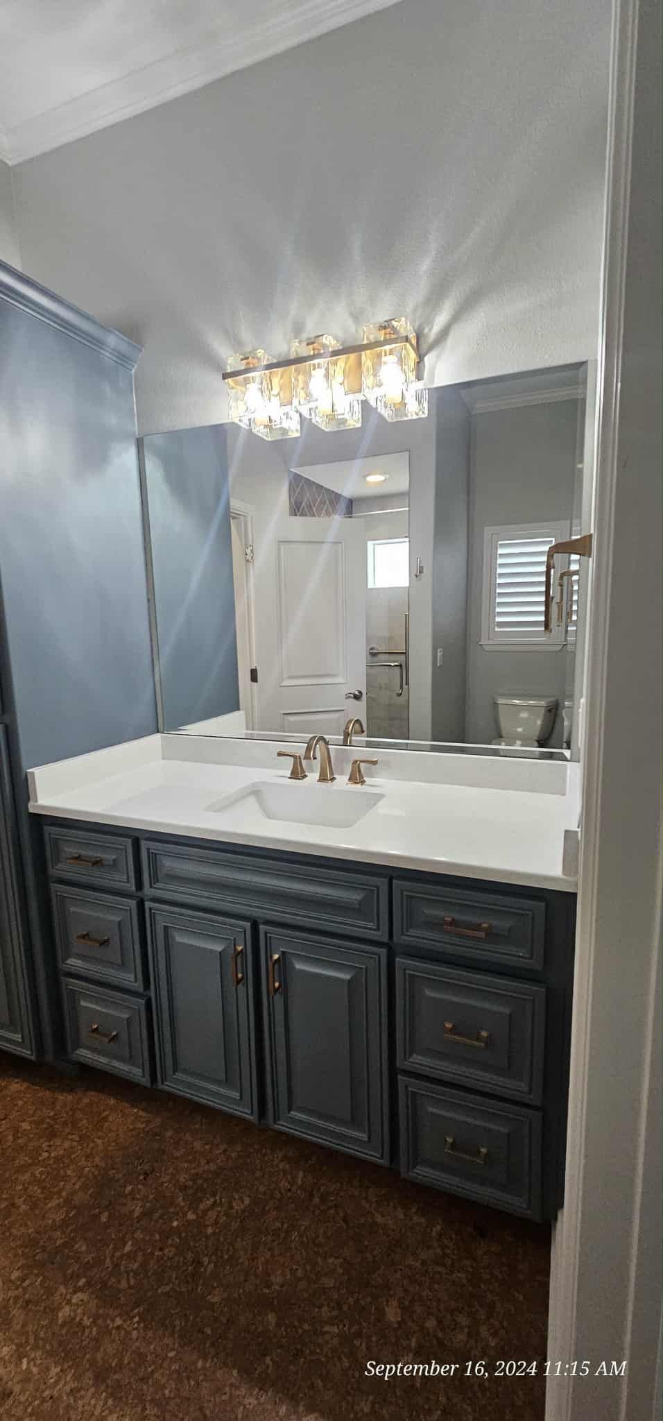 Walk-in closet with glass doors, clothing on hangers, drawers, dressing table. Neutral colors, modern design.