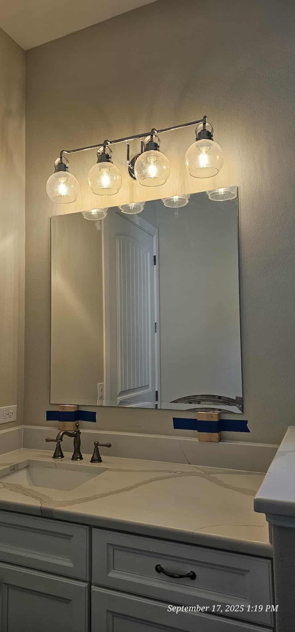 Bathroom with a mirror, vanity, and a light fixture with four glass globes.