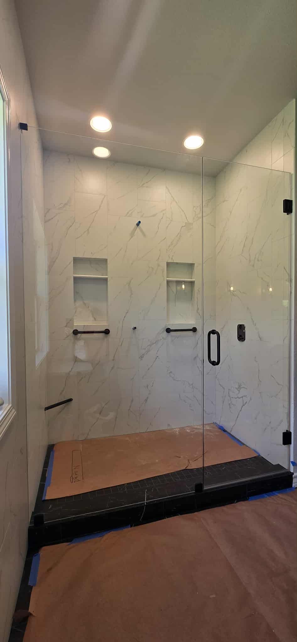 A modern bathroom with a glass shower enclosure and marble-like walls.