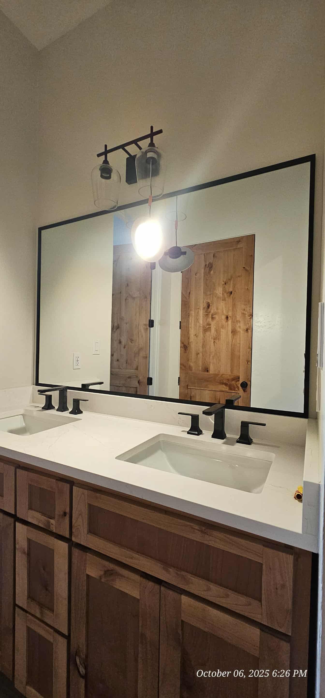 Bathroom vanity with a large mirror, dual sinks, and wooden cabinets.