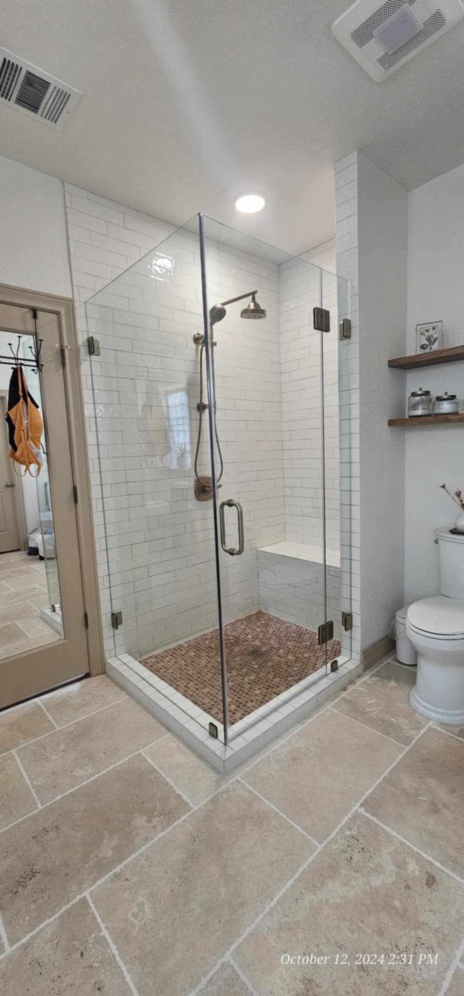 Corner shower with pebble floor, glass walls, and stone-tiled floor.
