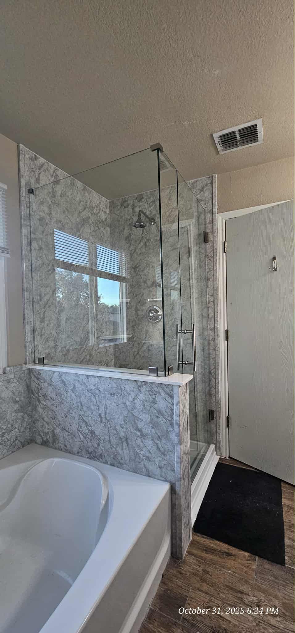 Bathroom with a glass shower, soaking tub, and mosaic tile walls.