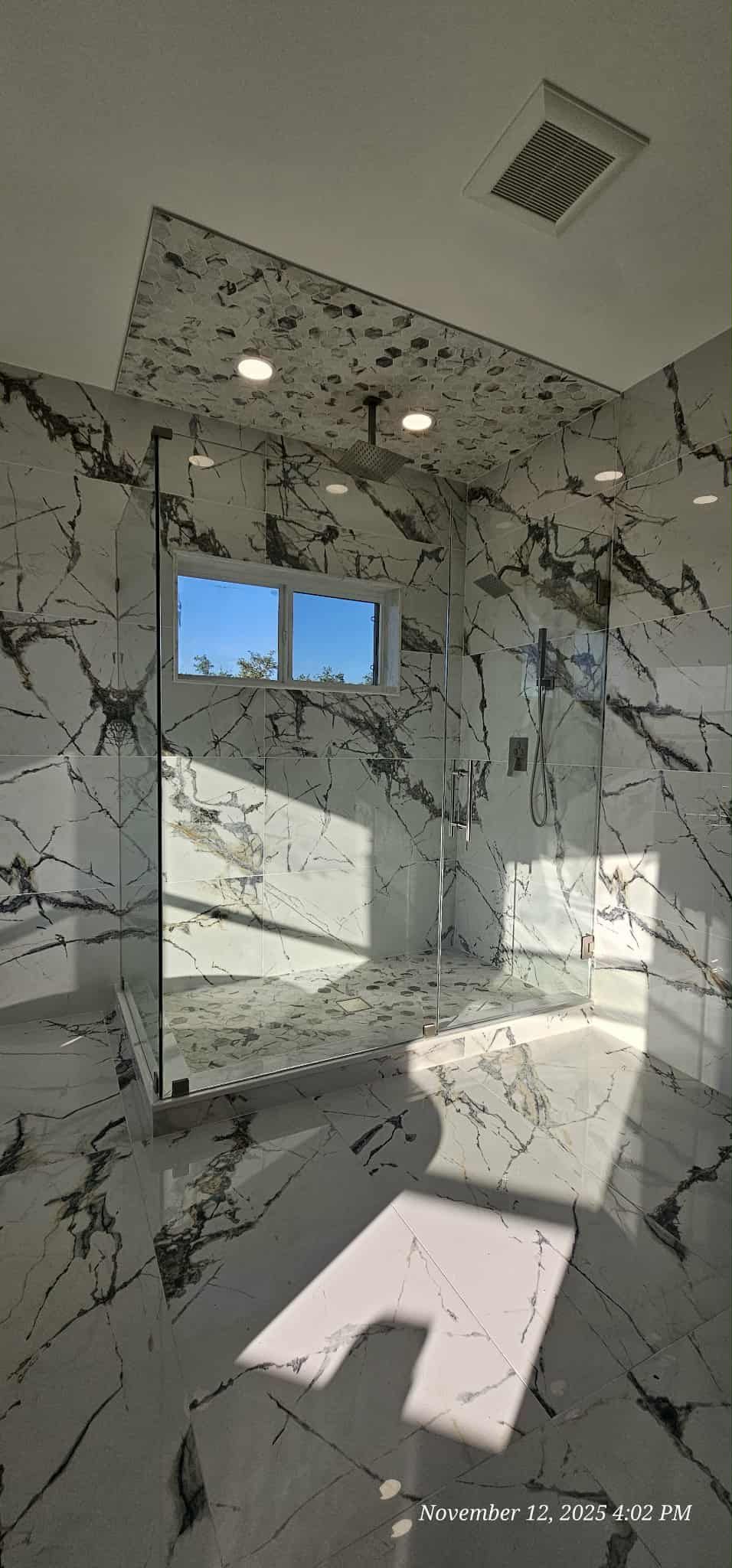 Bathroom with marble walls and a small window, light shining on the floor.