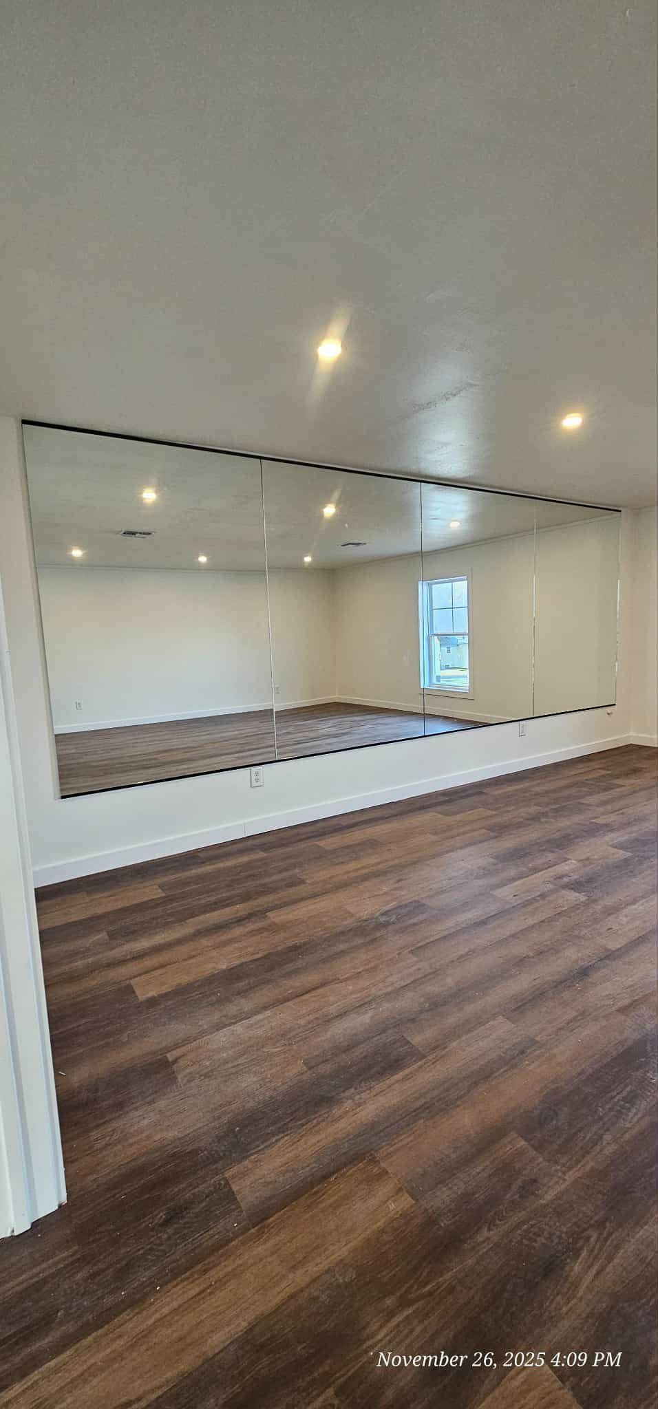 Room with wood floor and a large mirror.