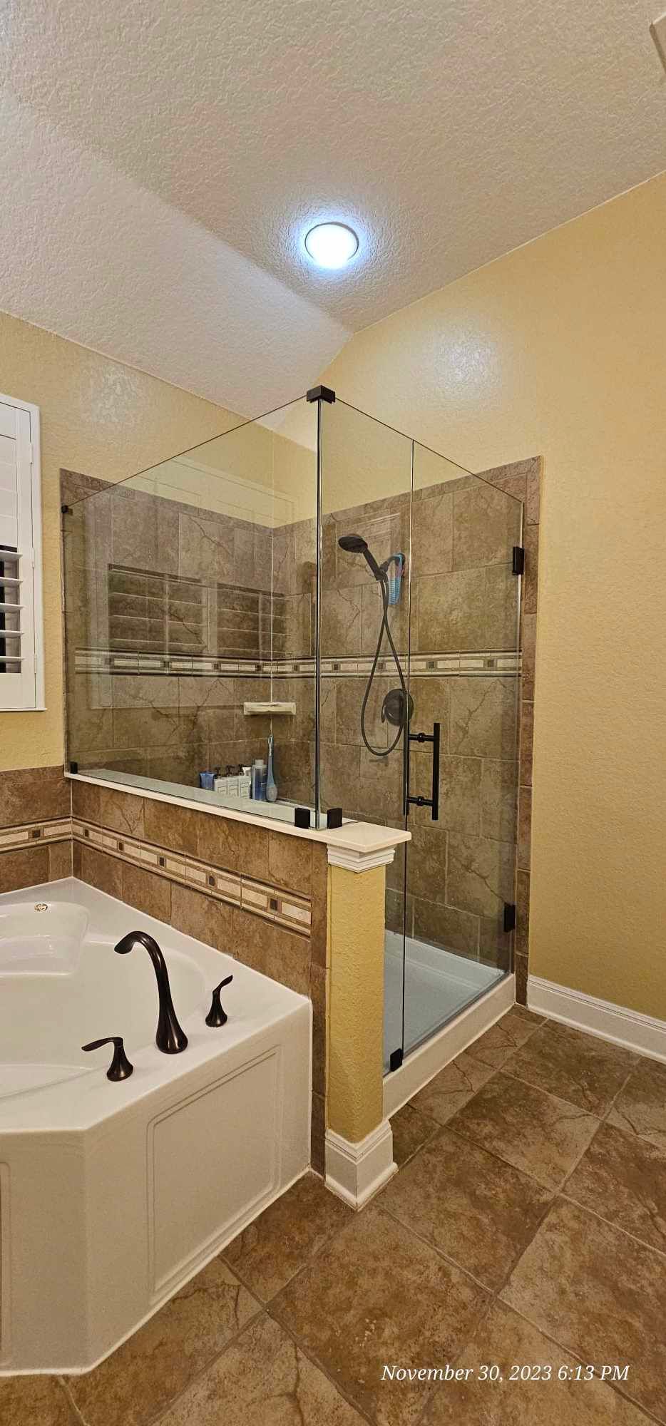 Bathroom with a corner shower and a bathtub, featuring glass doors and tiled walls.