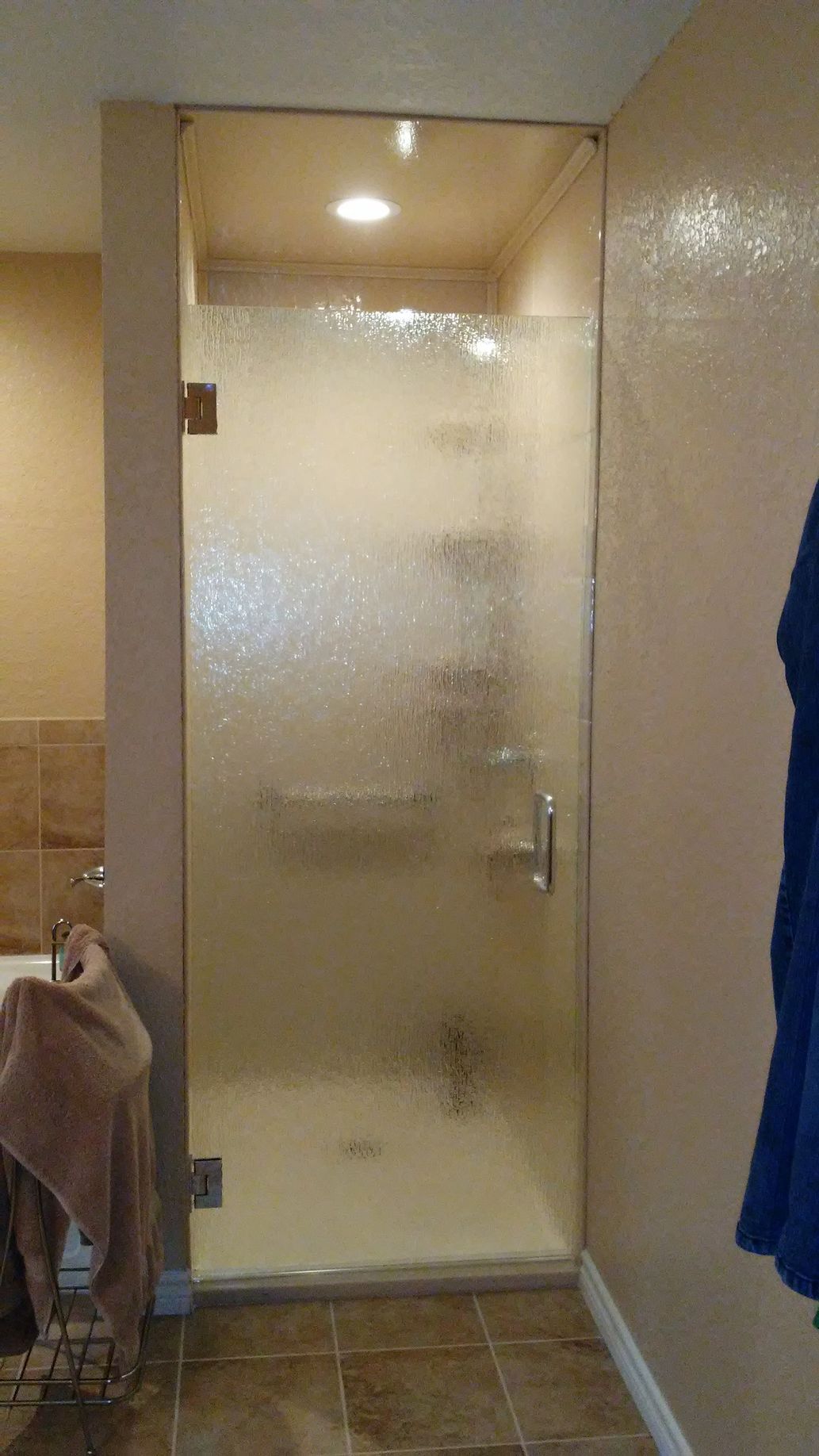 Frosted glass shower door in a bathroom with beige walls and tile floor.