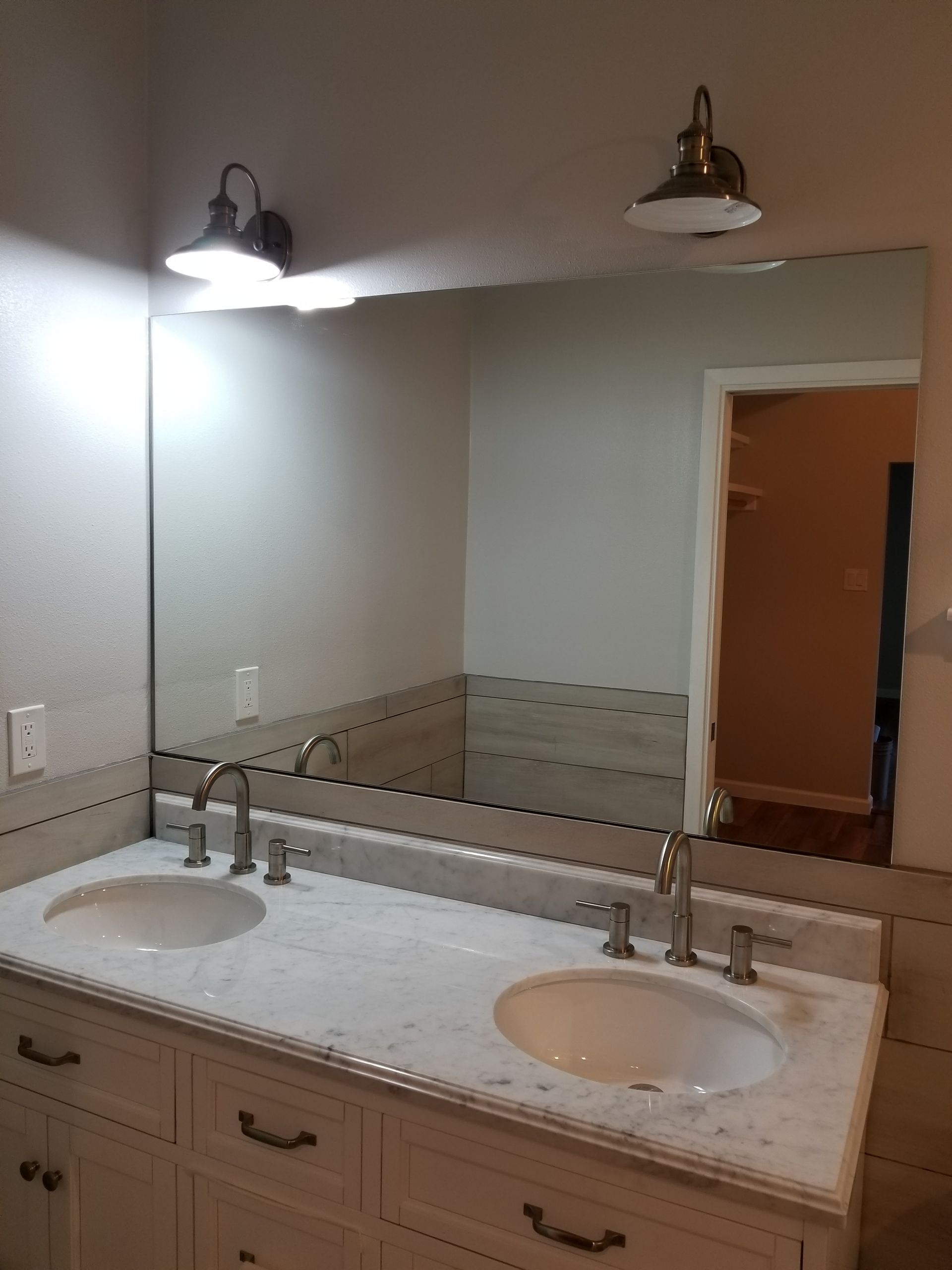 Bathroom vanity with two sinks, a large mirror, and two sconce lights.