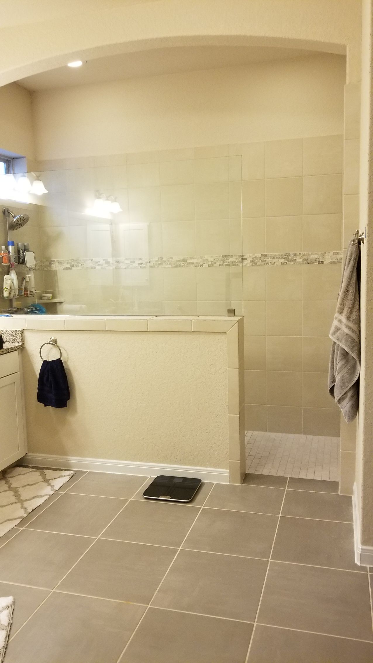 Bathroom with tiled walls and floor, a walk-in shower, and a scale.