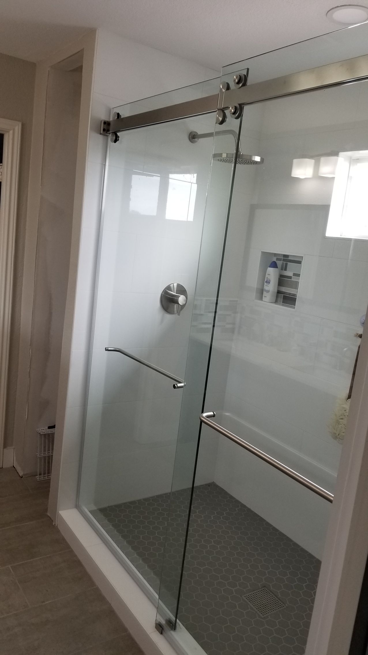 Shower with sliding glass doors, chrome hardware, and gray tiled floor and walls.