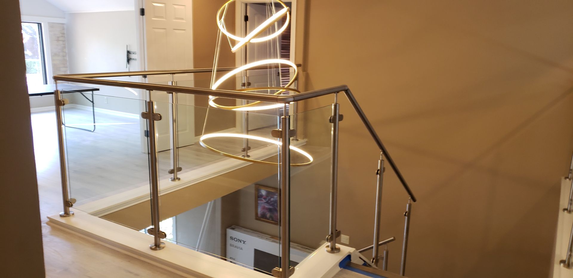 Walk-in closet with glass doors, clothing on hangers, drawers, dressing table. Neutral colors, modern design.