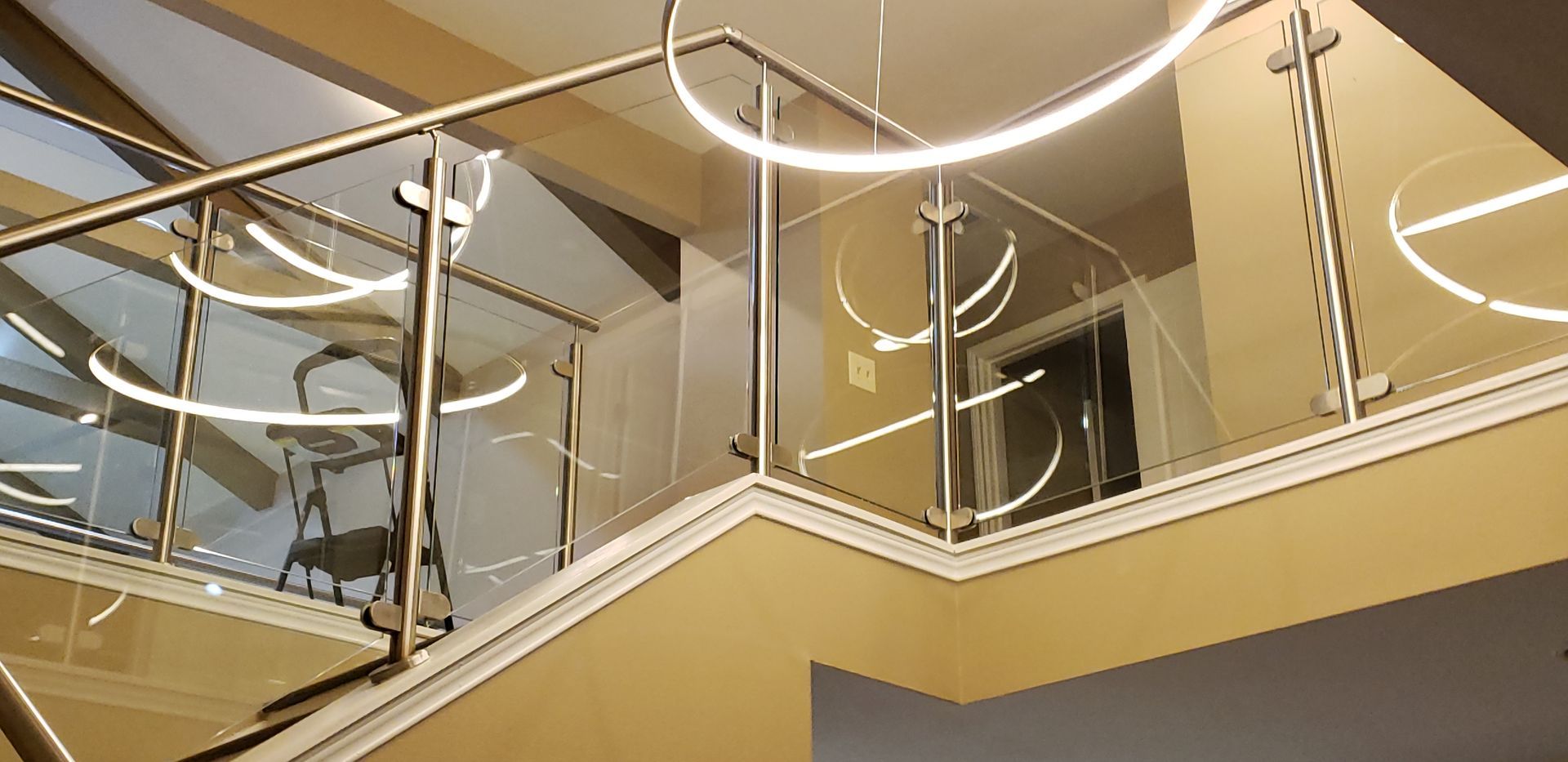 Staircase with glass railing and circular, illuminated light fixtures.