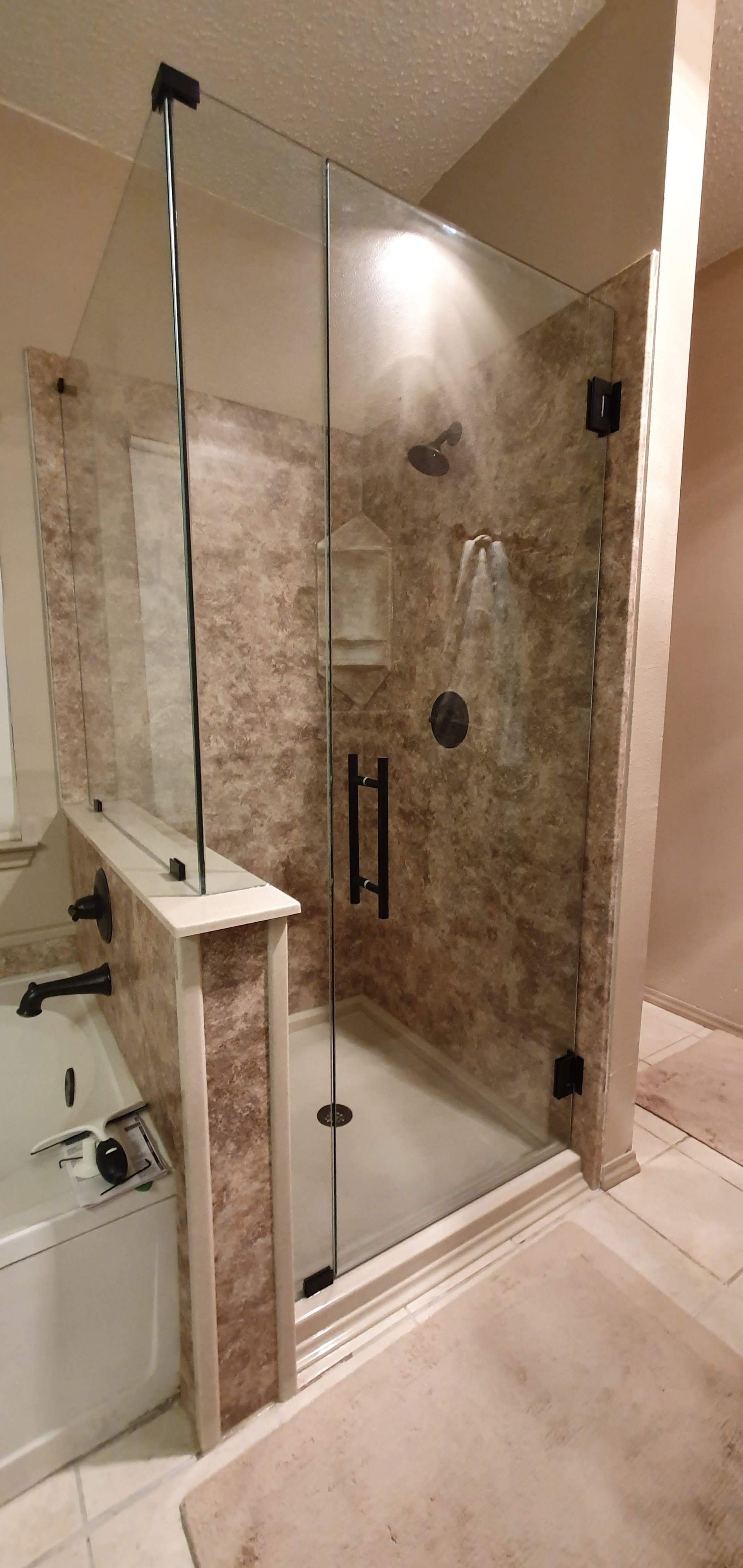 A luxurious modern bathroom shower with a glass door and beige tile.