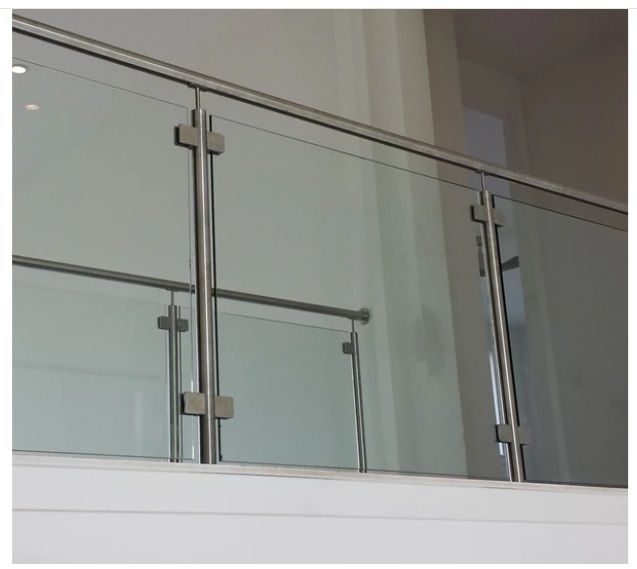 Glass and metal railing on a balcony, with a white wall in the background.