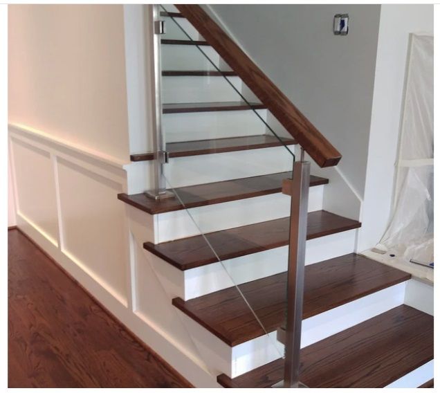 Staircase with wooden steps and railing, glass panels. White walls, dark wood floor.
