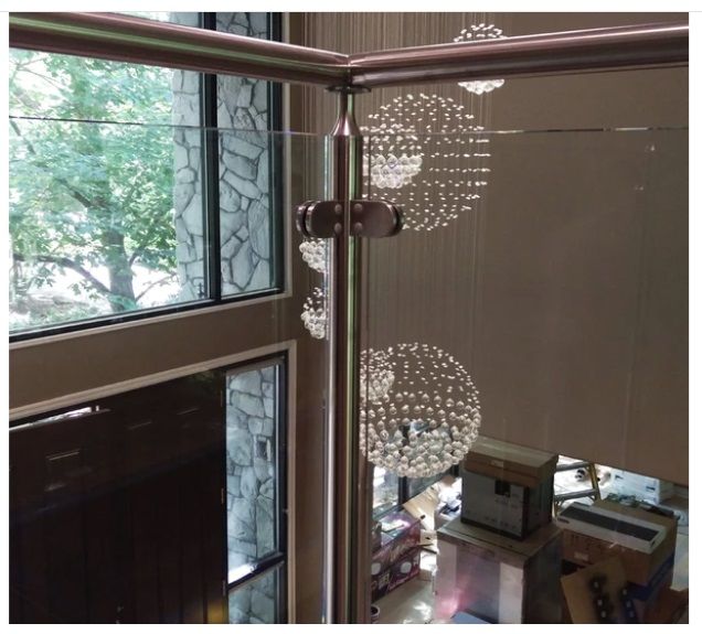 Interior view with glass railing and crystal globe chandeliers. Large window and neutral walls are visible.