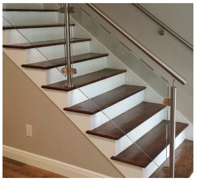 Staircase with wood steps and white risers. Stainless steel railing and cable balusters.