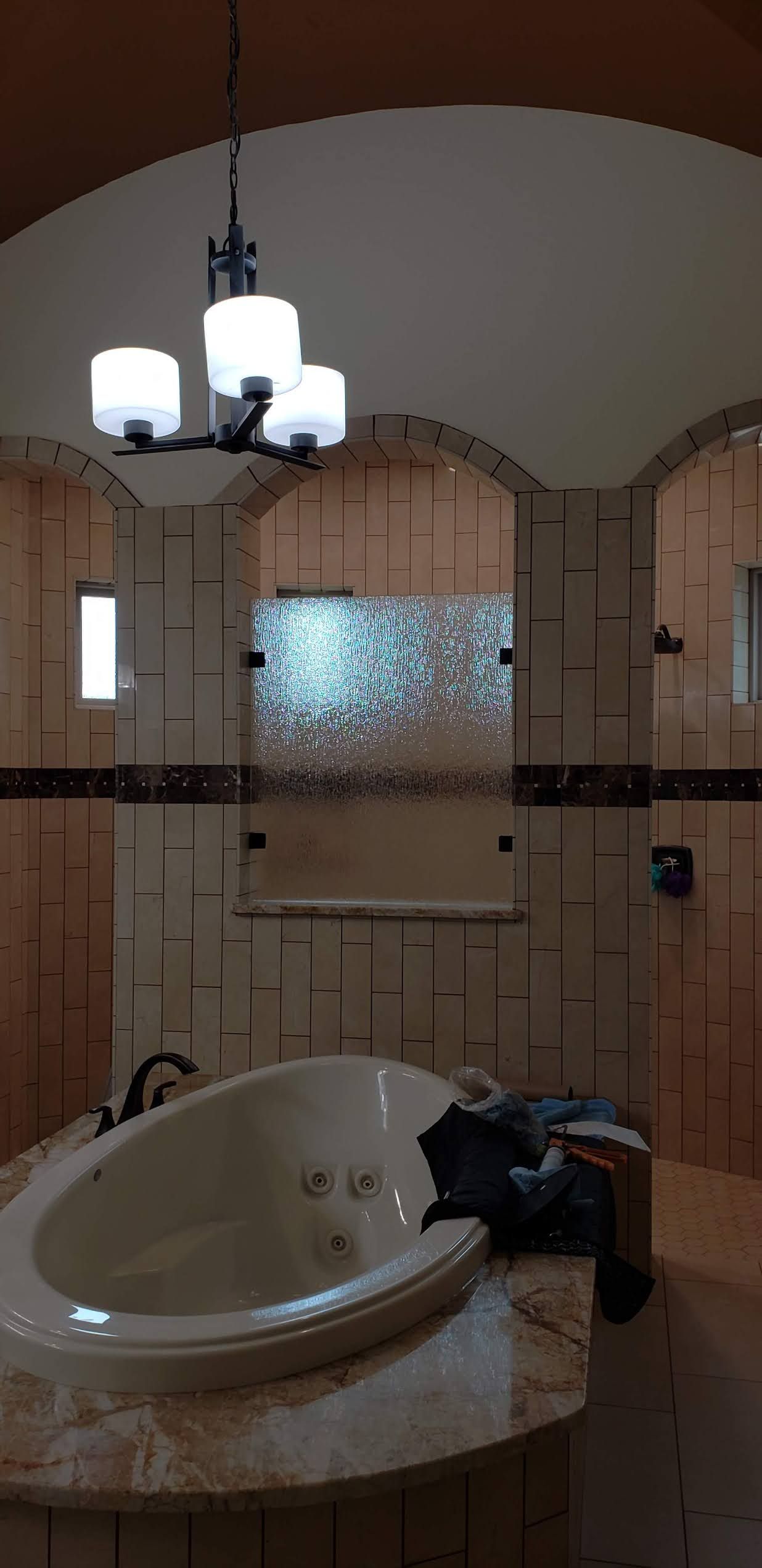 Bathroom with jacuzzi tub, wooden walls and a chandelier.