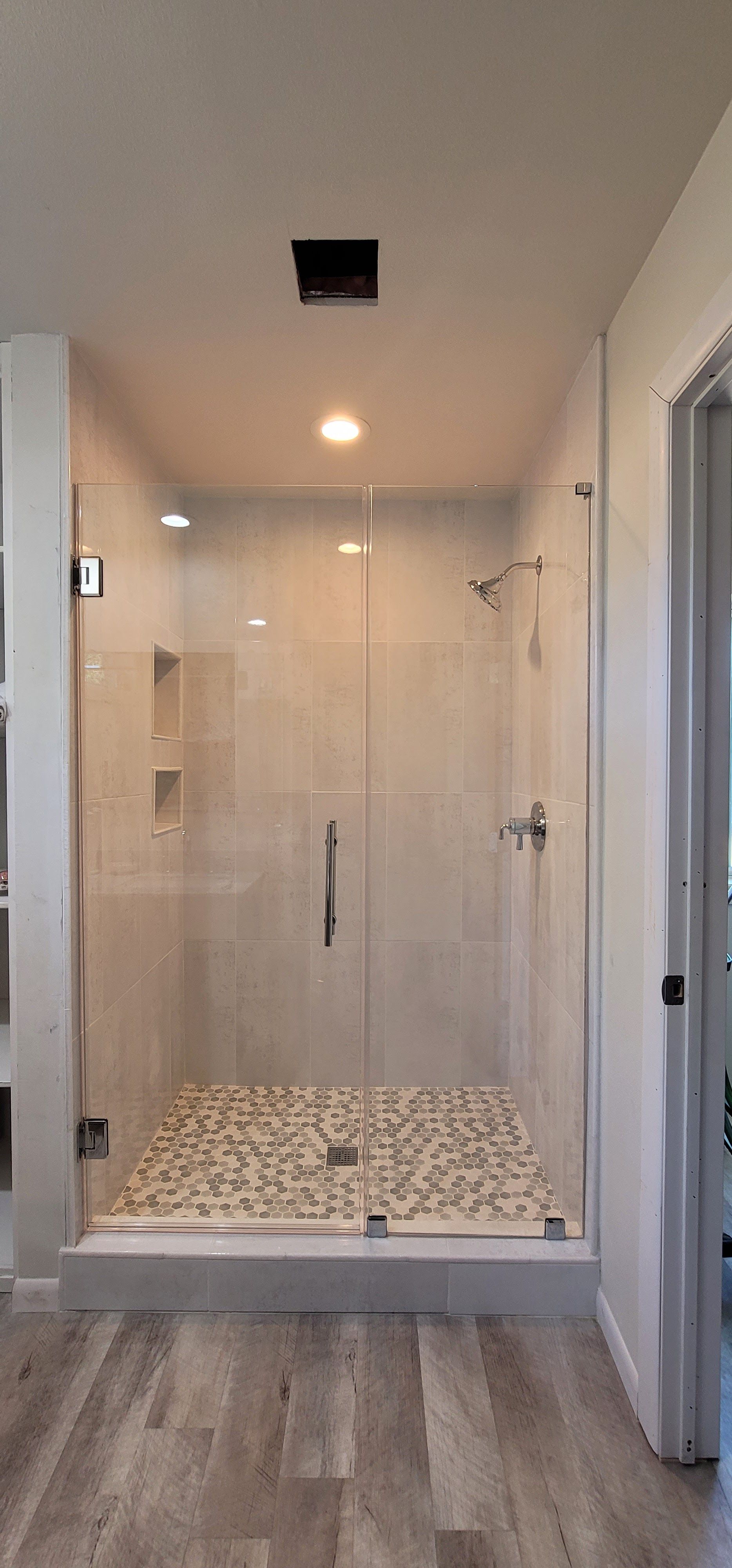 Modern bathroom with a glass shower enclosure and a pebble floor.