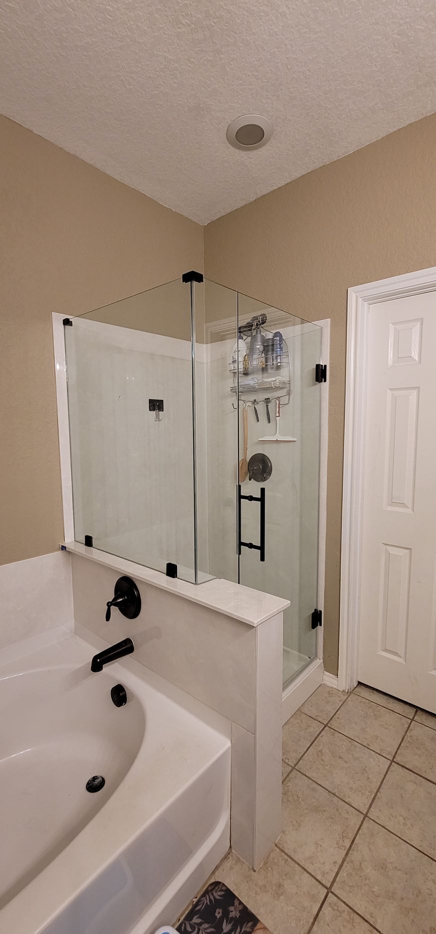 A bathroom featuring a shower with a glass door, a bathtub, and tan walls.