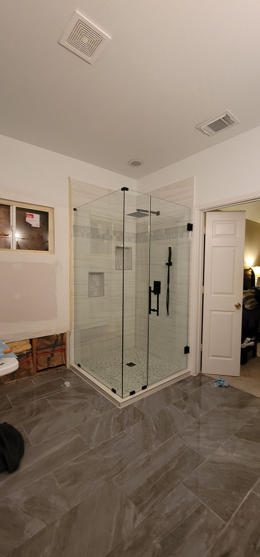 Modern bathroom with a glass shower, gray tiled floor, and white walls.