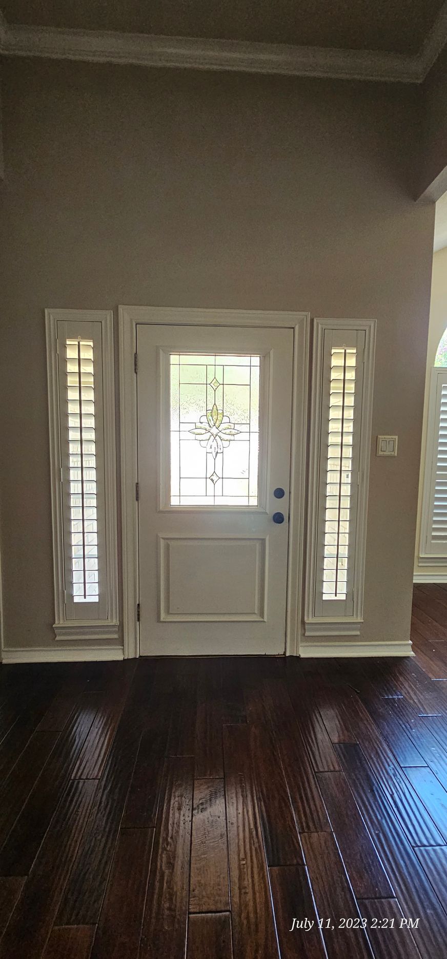 Entryway with white door and sidelights, dark wood floor, and neutral walls.