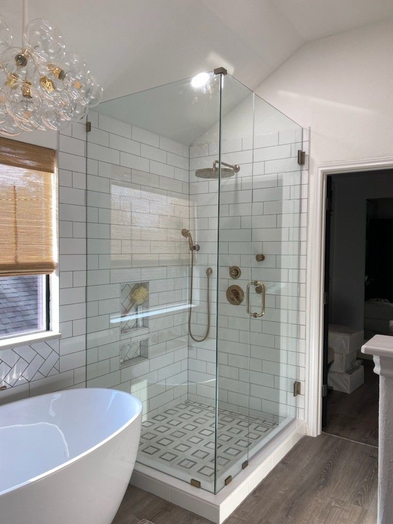 Modern bathroom with white subway tile shower, glass doors, and a freestanding tub.