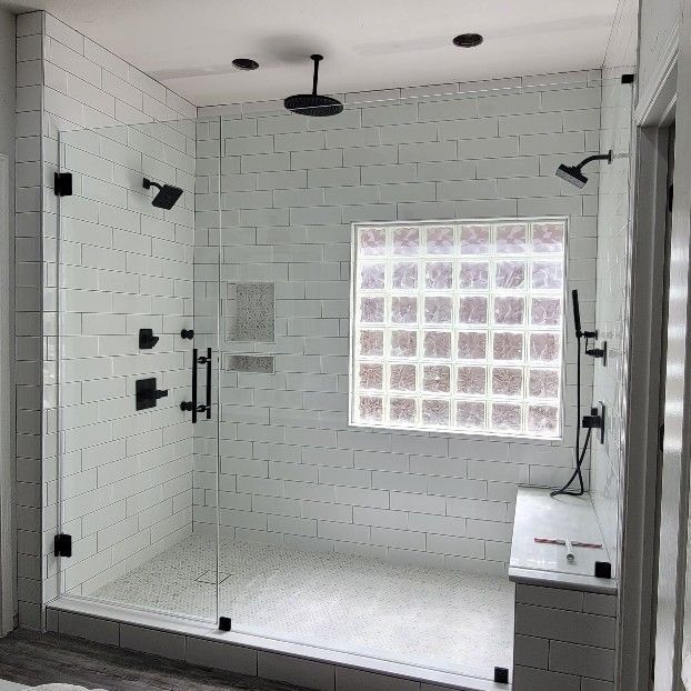 Modern bathroom with white subway tile shower, glass doors, and black fixtures.