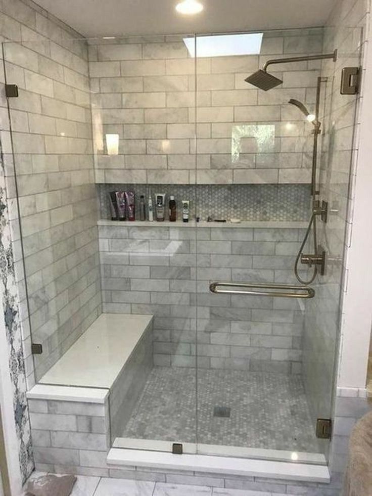 Shower with marble-look tile, glass doors, built-in bench, and niche for toiletries.