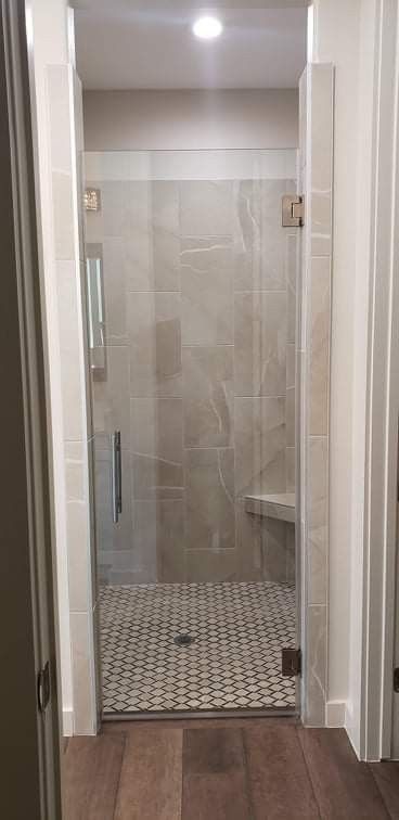 Shower with glass door, tiled walls, and pebble floor. A built-in bench is visible.