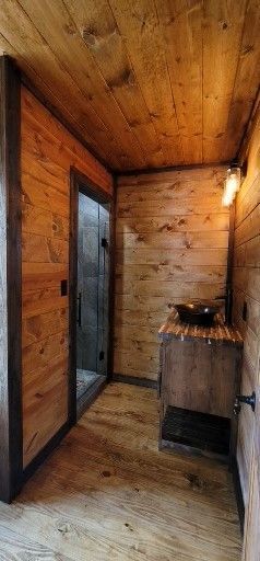 Wooden-paneled bathroom with a shower, sink, and wood vanity.