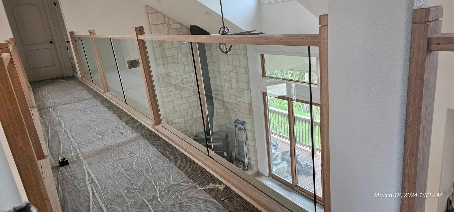 Interior hallway with glass railing and window overlooking the outdoors.
