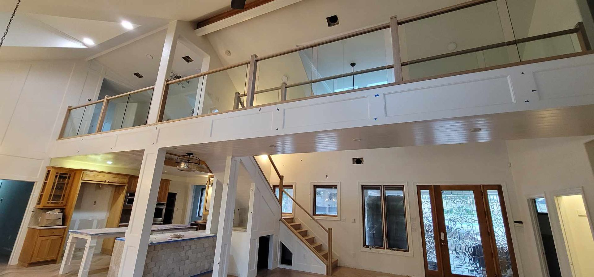 Interior view of a modern home with a loft, glass railings, and natural light.
