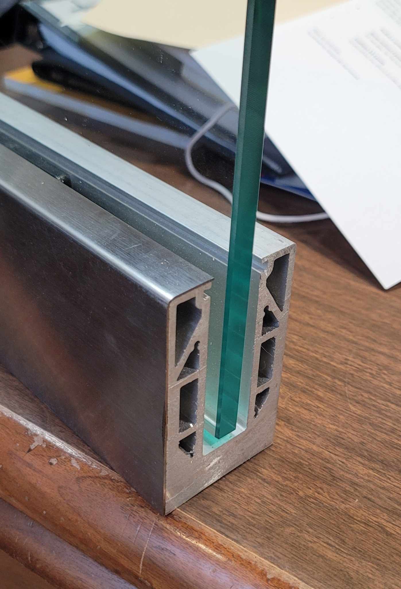 Aluminum railing profile holding a green glass panel.