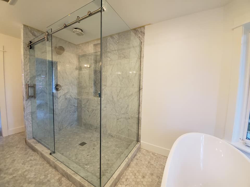 Spacious bathroom with glass shower, marble tile, and freestanding tub.