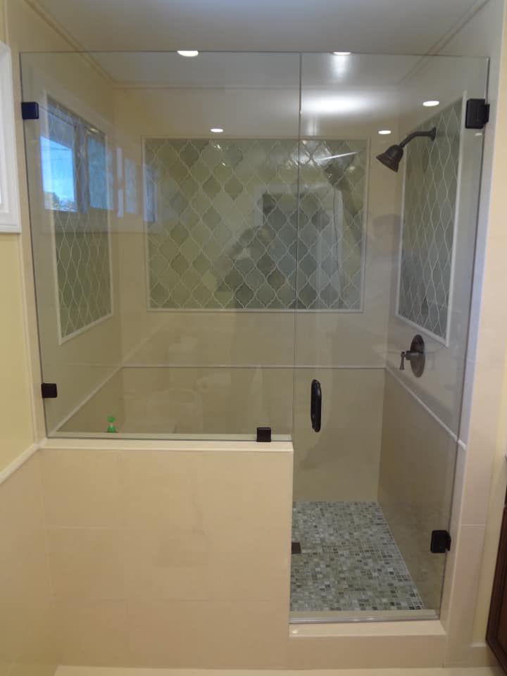 Glass shower enclosure with mosaic tile and pebble floor.
