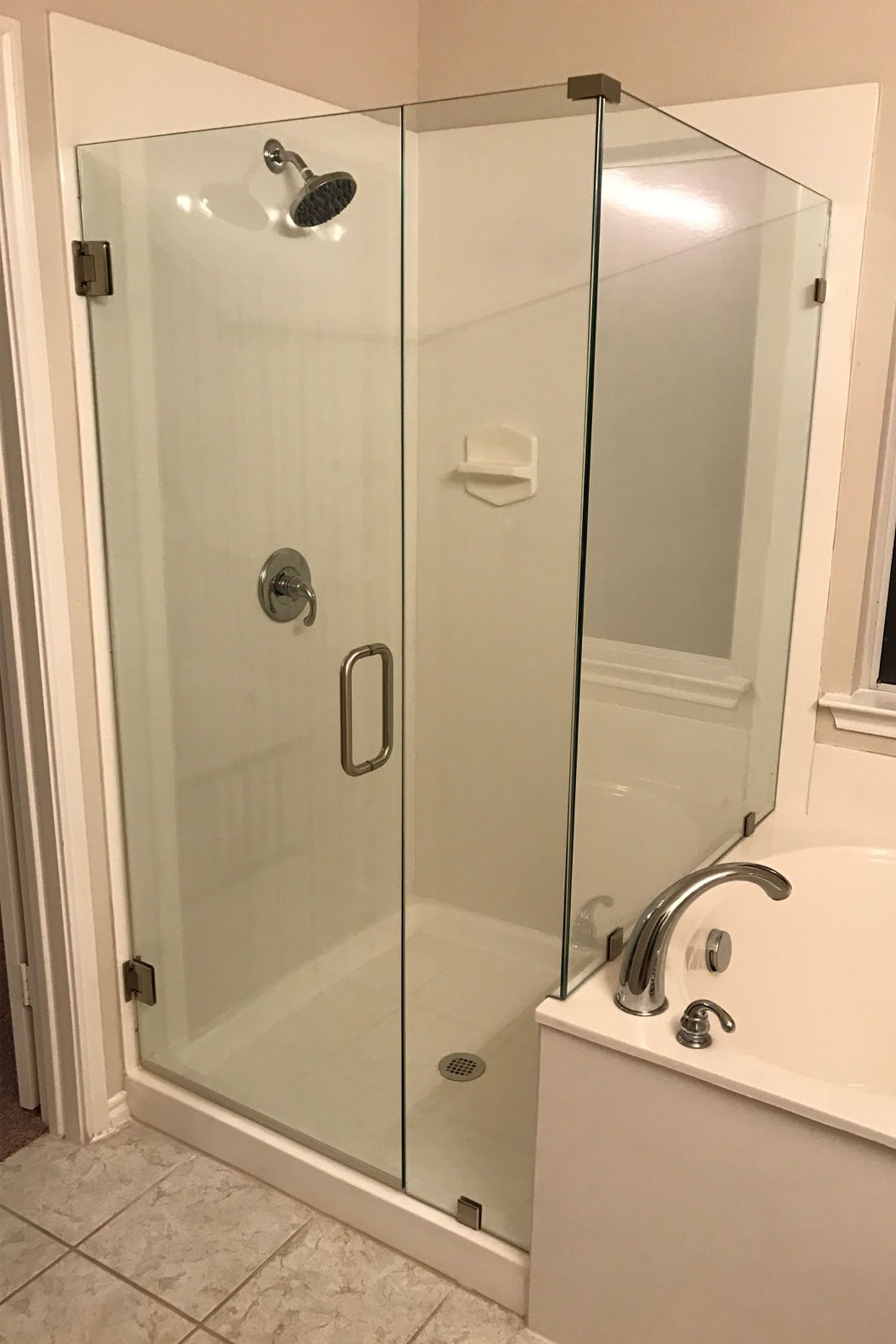 Corner shower with glass doors, white walls, and silver fixtures.