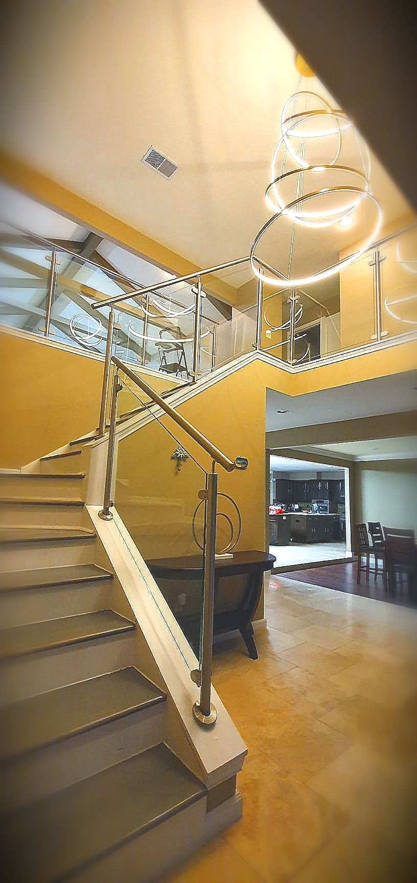 A staircase with a stainless steel railing in a yellow-walled interior.