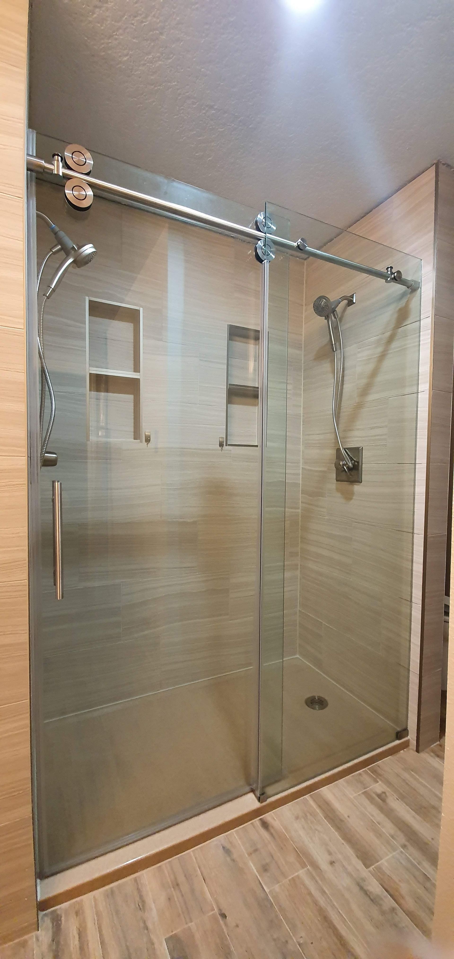Shower enclosure with sliding glass doors, stainless steel hardware, and built-in niches.