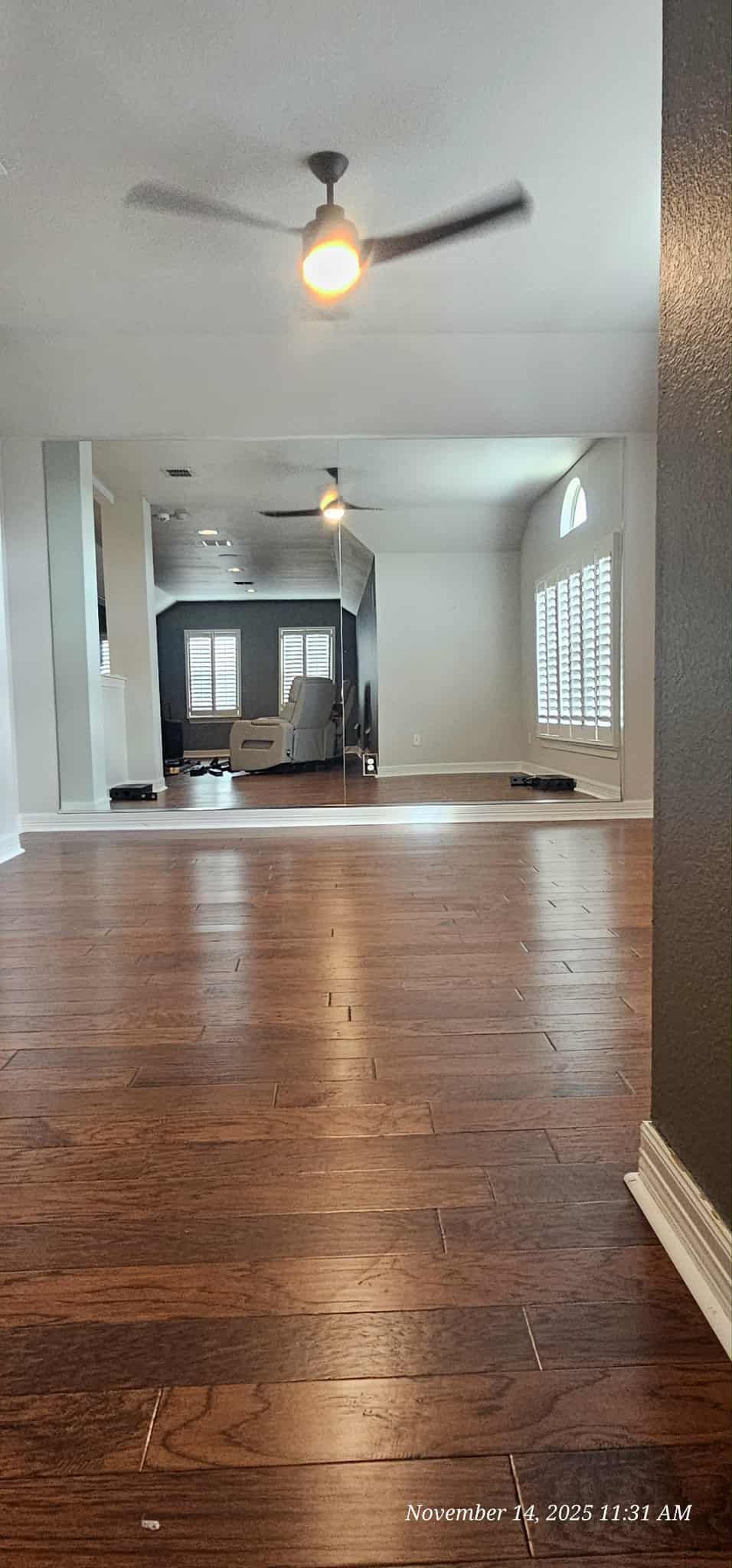 Interior view of a room with hardwood floors, white walls, and a ceiling fan.