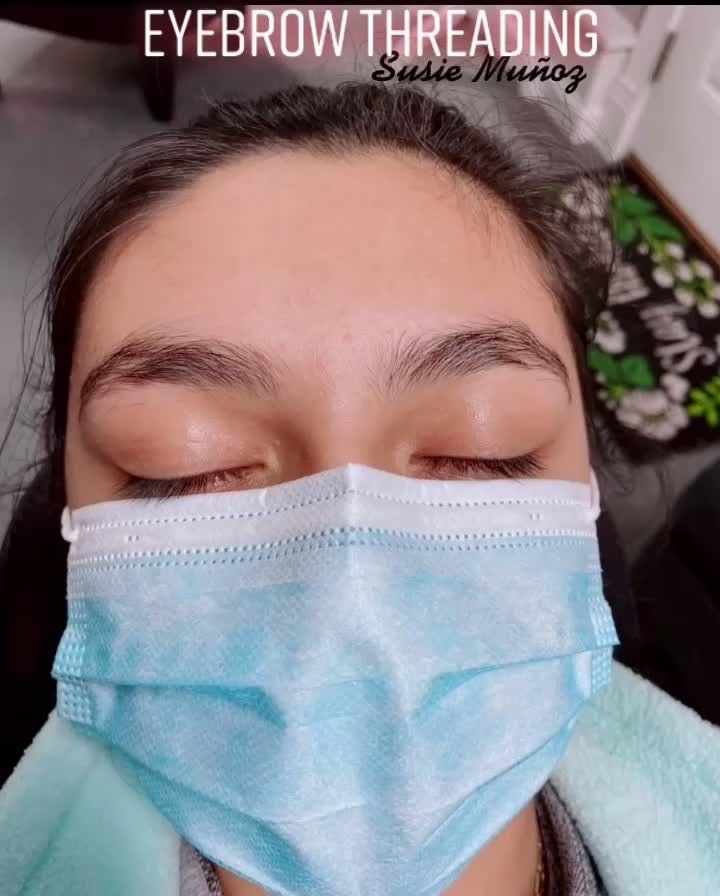 A woman is getting her eyebrows tattooed with a machine.