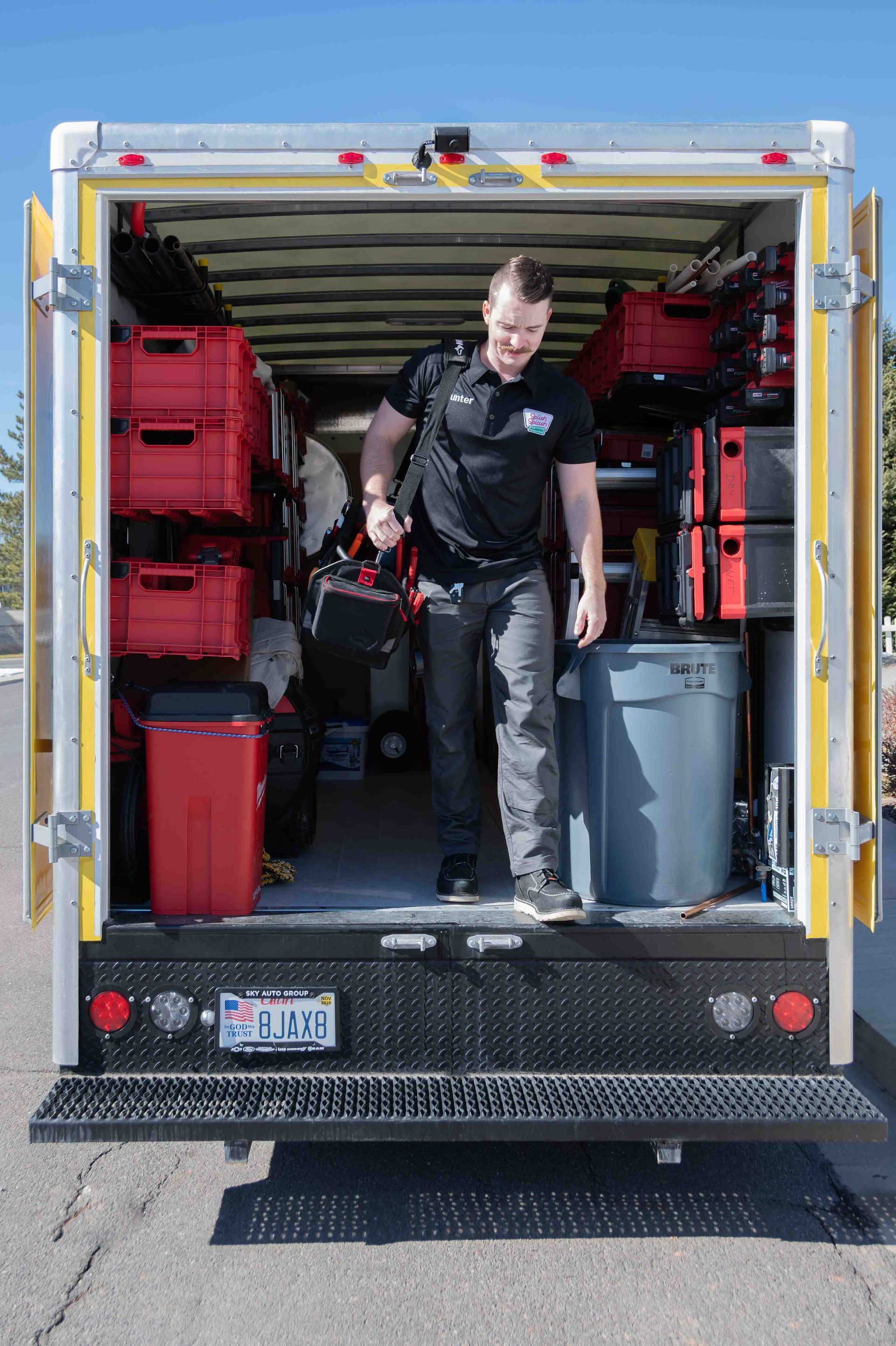 Man stepping out of a service truck, which is packed with equipment in red and grey containers.