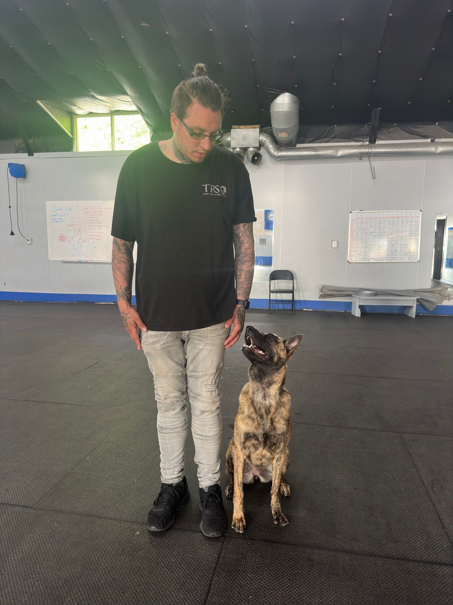 A man is standing next to a dog in a room.