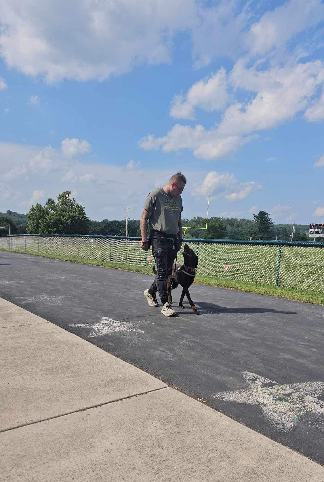 A man is walking a dog on a leash on a sidewalk.